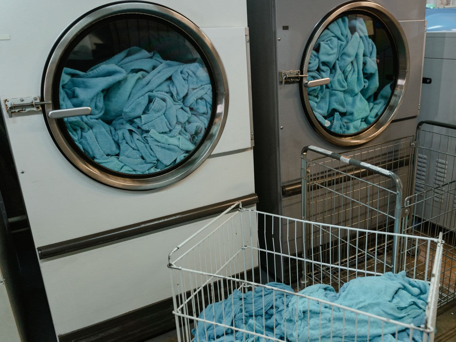 Commercial laundry machines loaded with blue towels